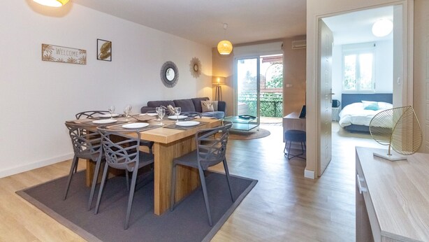 Ein modernes Wohnzimmer mit Essbereich, einer Couch und einem Balkon mit Blick.