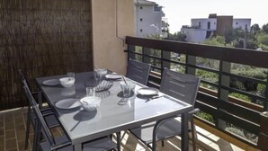 Un balcón con mesa y sillas para cuatro, y vista a edificios al fondo.