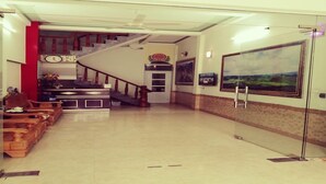 Un vestíbulo de hotel con mostrador de recepción, área de descanso, escalera y un cuadro grande en la pared.
