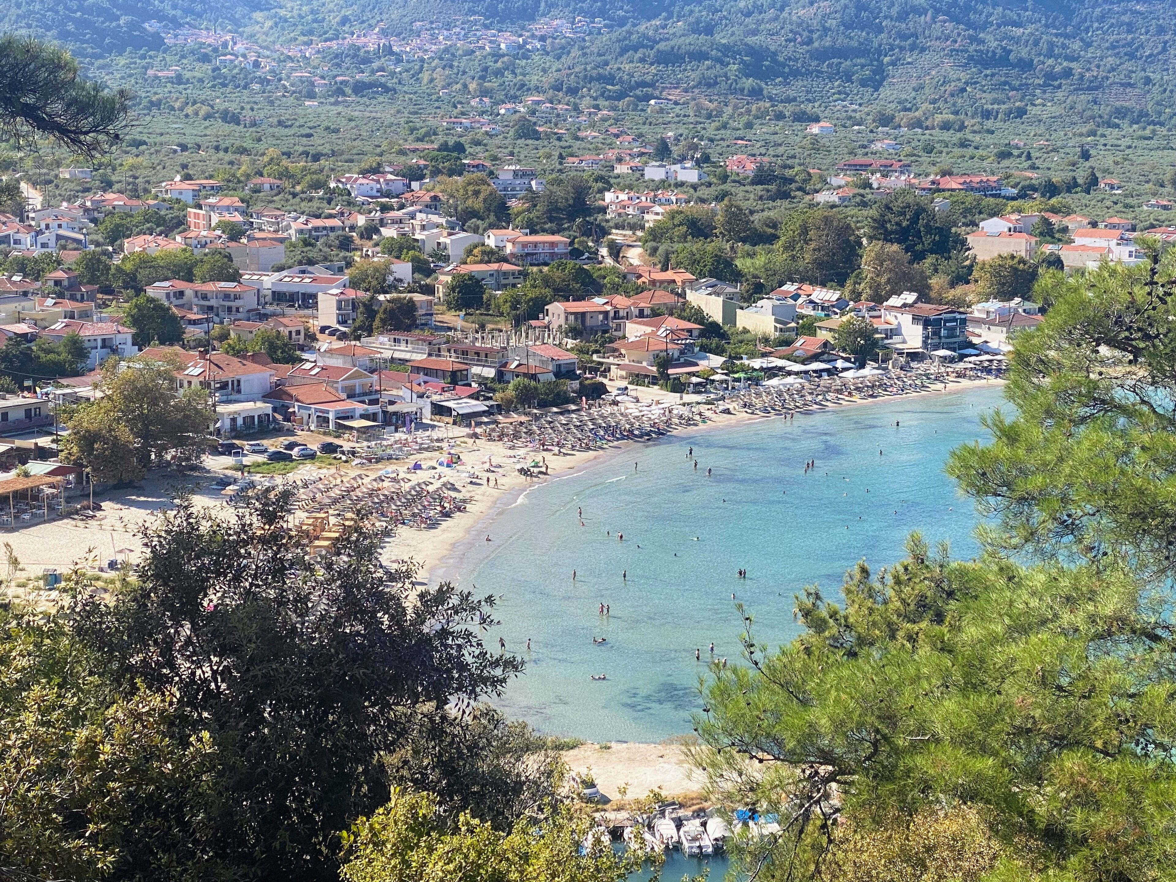 Un pueblo costero con playa, casas y montañas al fondo.
