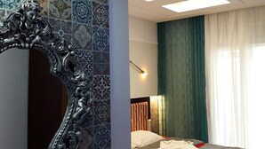 A bedroom with a bed, a mirror, and patterned tiles on the walls. - Blue Sea Beach Hotel (Thasos)