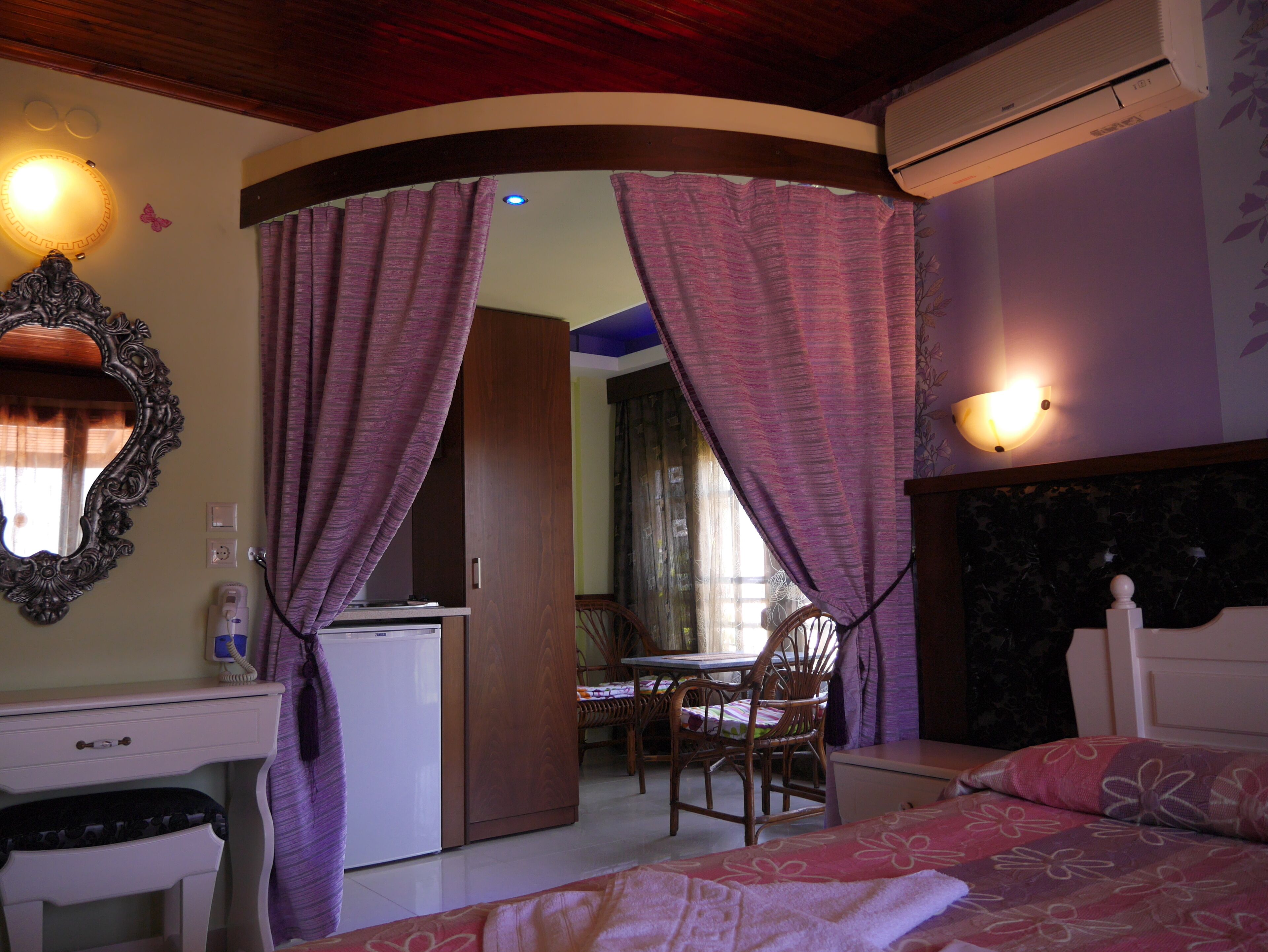 A bedroom with a bed, a desk, a chair, and an air conditioning unit.