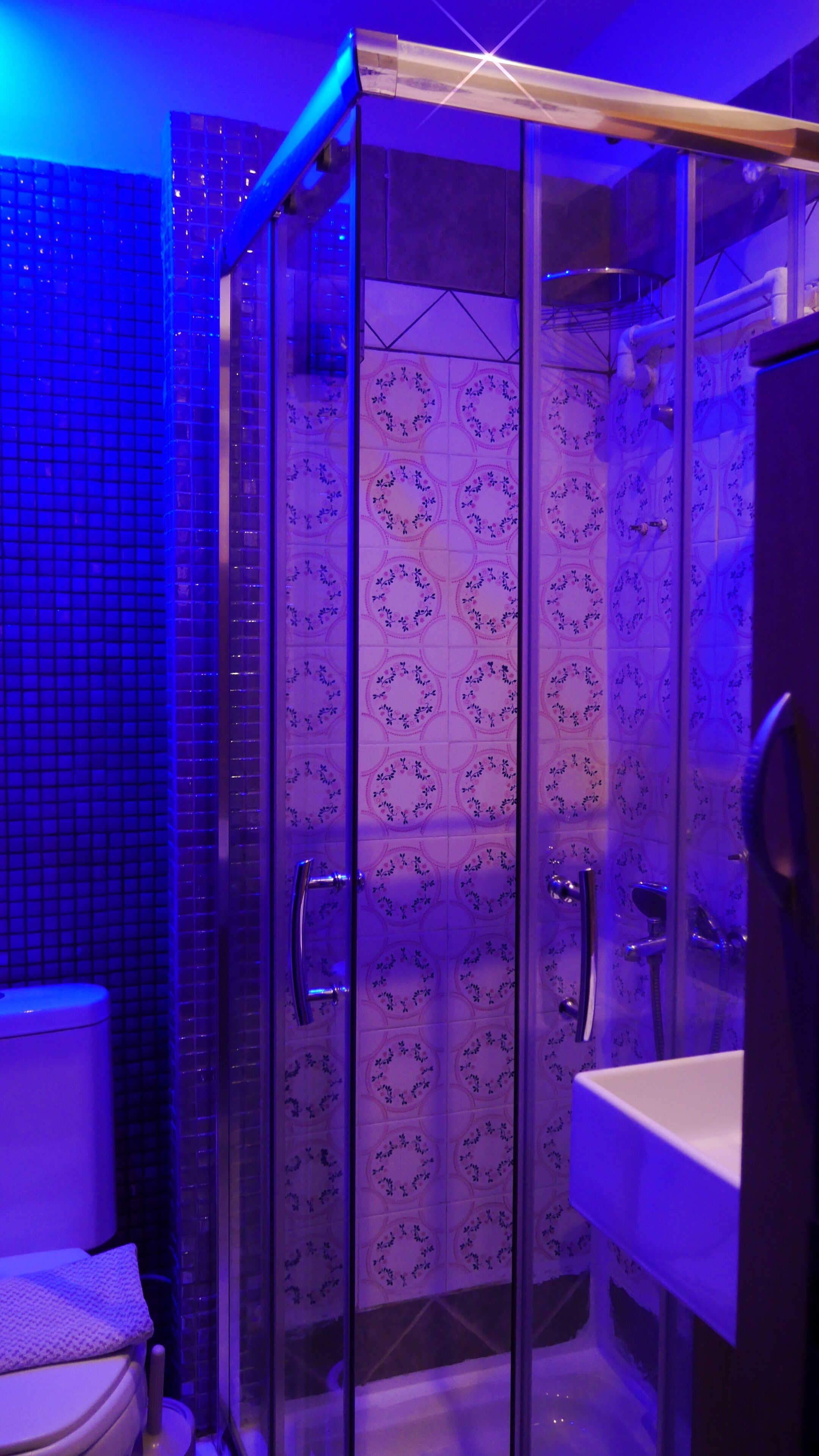 Un baño moderno con cabina de ducha de vidrio, un lavabo blanco y un inodoro.