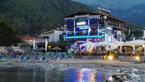A hotel with a poolside area, outdoor seating, and a view of the mountains. - Blue Sea Beach Hotel (Thasos)