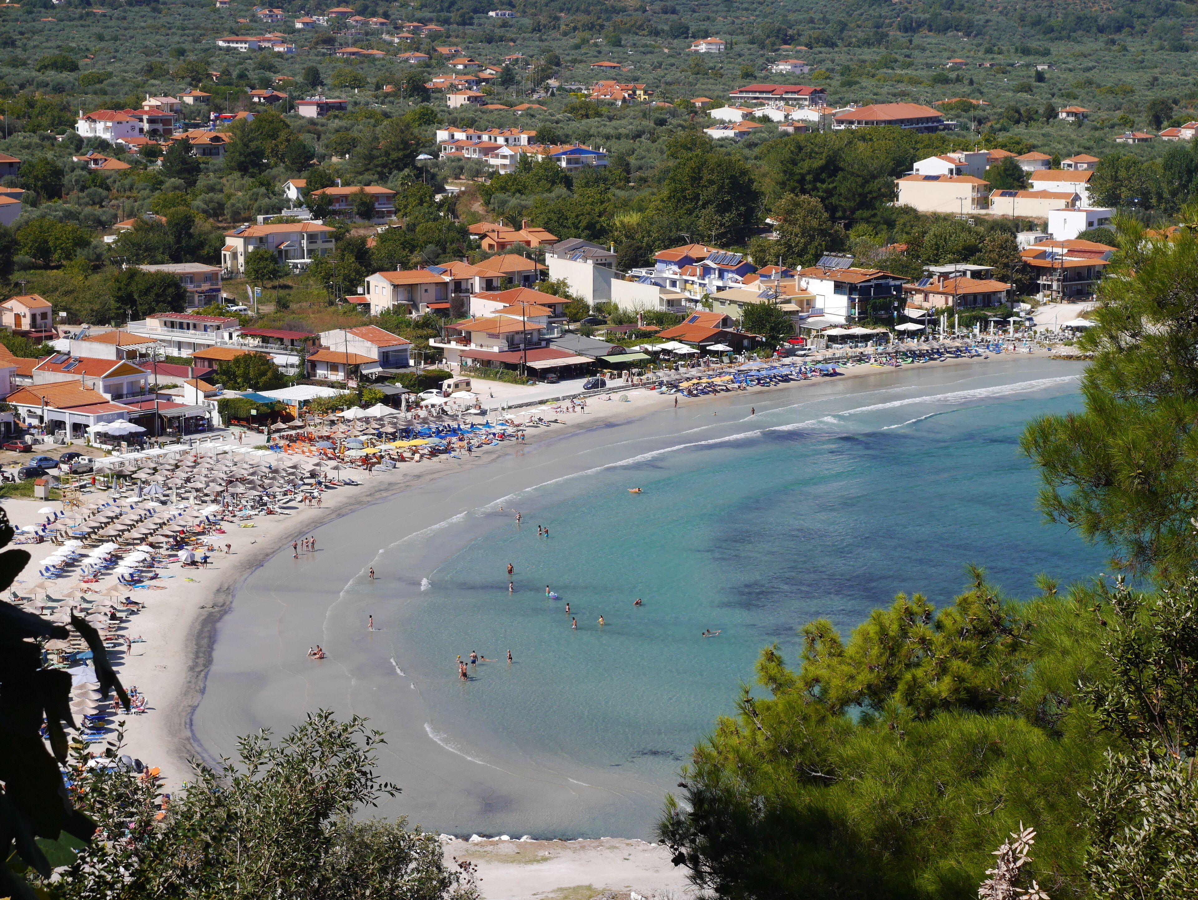 Un pueblo costero con playa, casas y una vista despejada del mar.