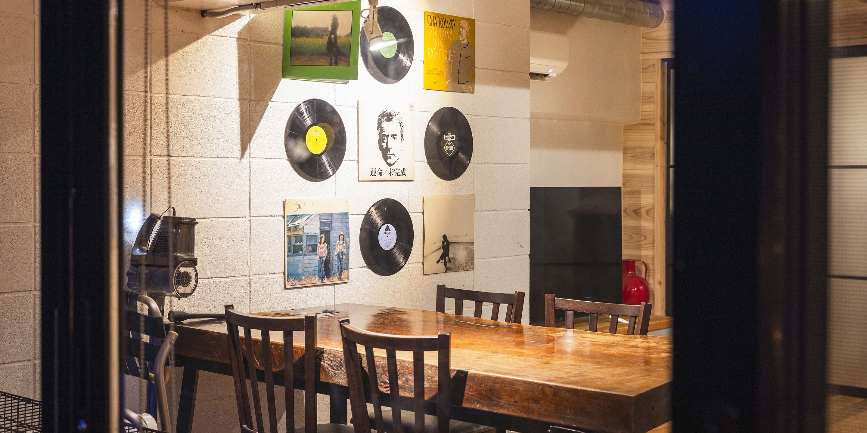 Un coin repas avec une table et des chaises en bois, entouré de murs décorés de pochettes de disques vinyles et de photos encadrées.