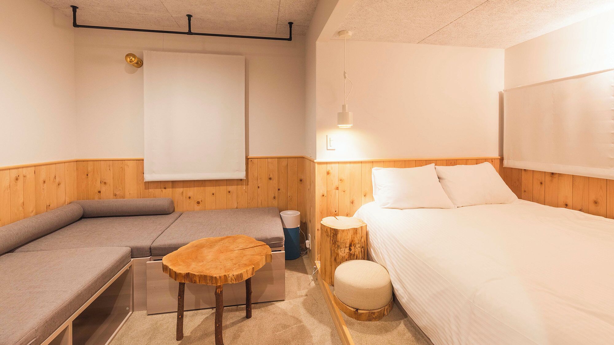 Une pièce comprenant un lit, un canapé, une petite table ronde et une lampe fixée au mur.