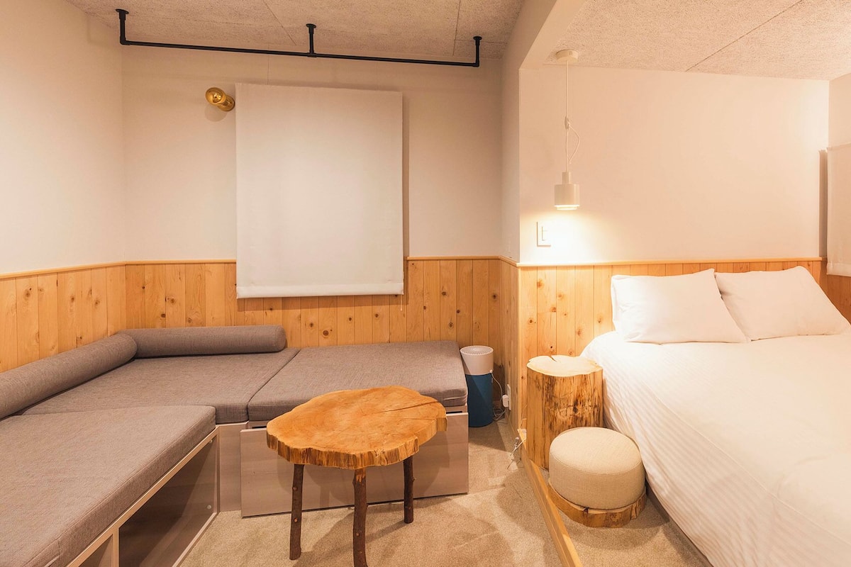 Een kamer met een bed, een slaapbank, een klein rond tafeltje en een wandlamp.