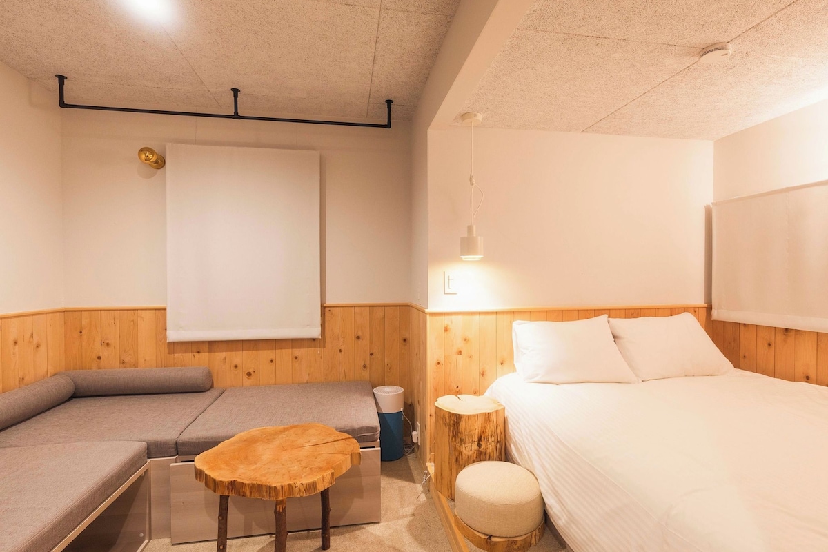 Een compacte kamer met een bed, een bank, een klein tafeltje en een lamp.