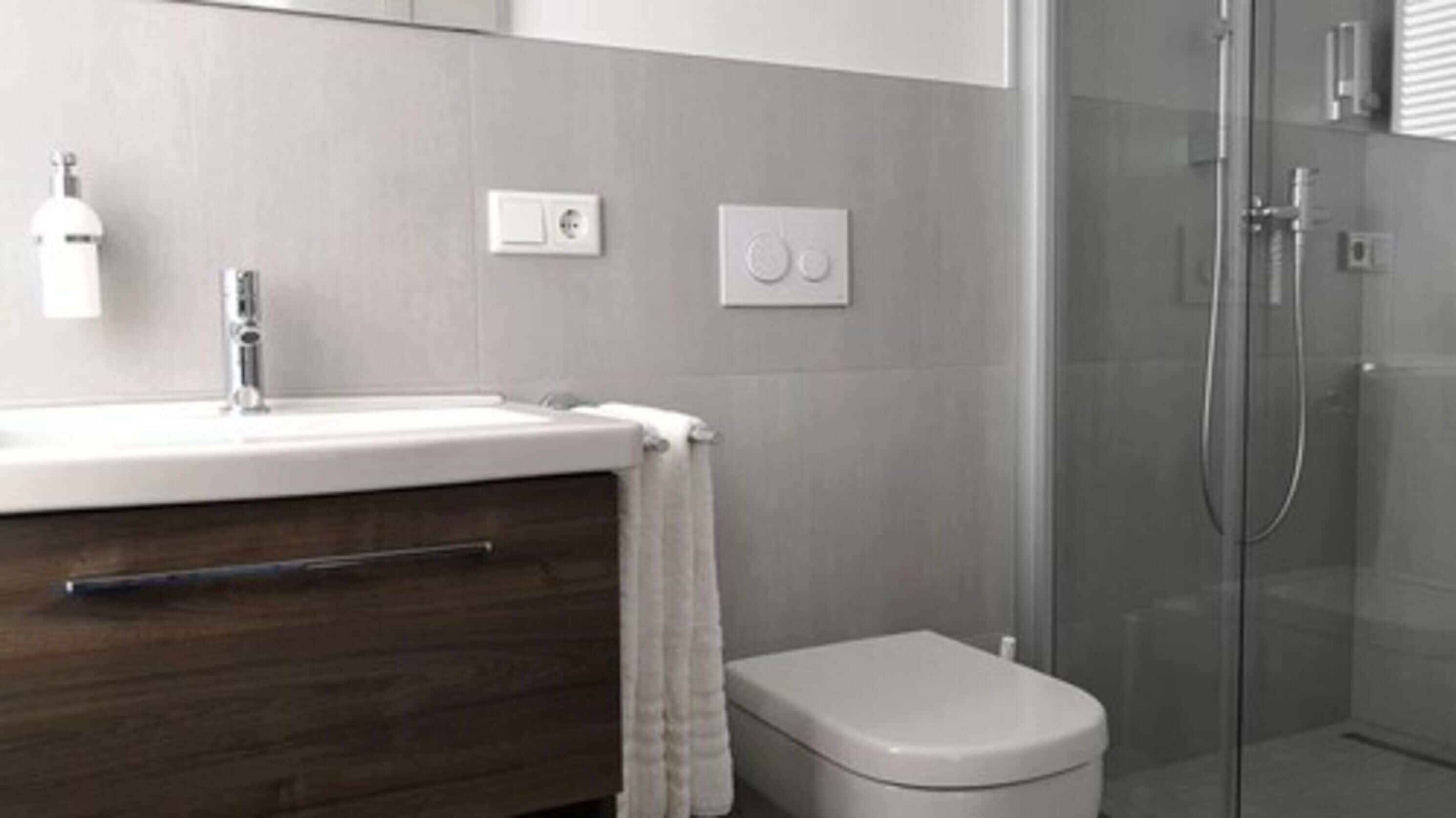 A modern bathroom with a sink, mirror, and toilet.