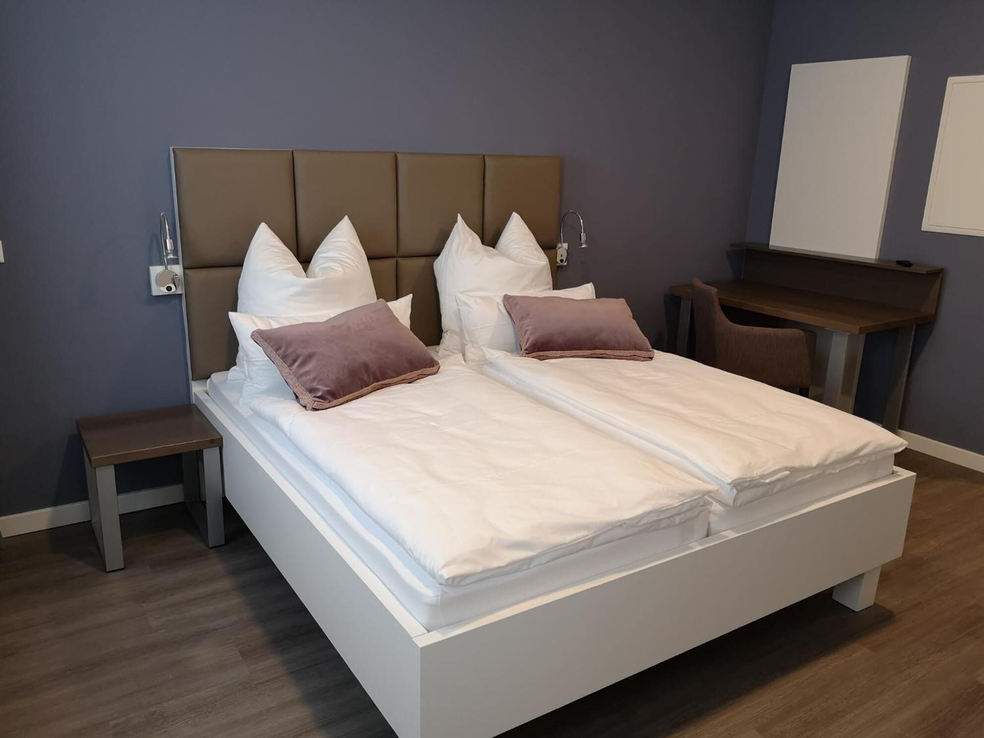 Habitación de hotel moderna con una cama grande, dos mesitas de noche, un escritorio y una silla.