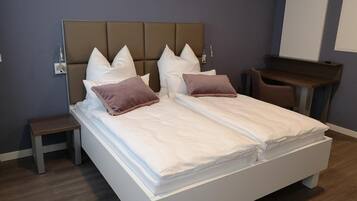 Ein modernes Hotelzimmer mit einem großen Bett, zwei Nachttischen, einem Schreibtisch und einem Sessel.