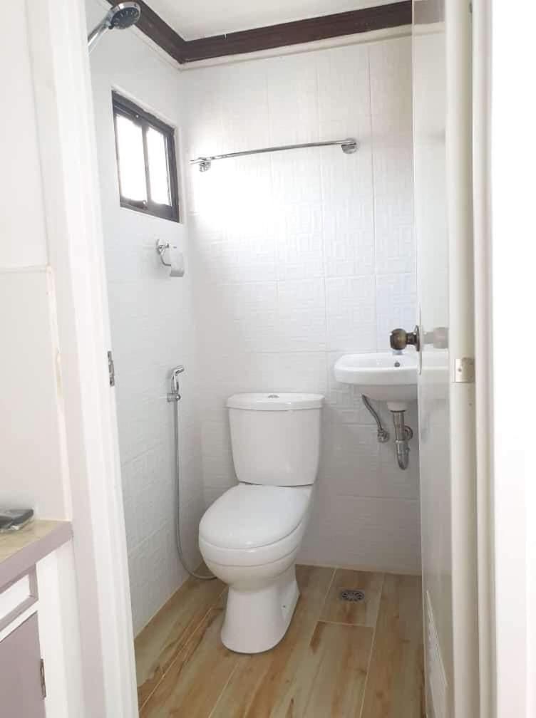 A small, enclosed bathroom with a toilet, a shower, and a sink.