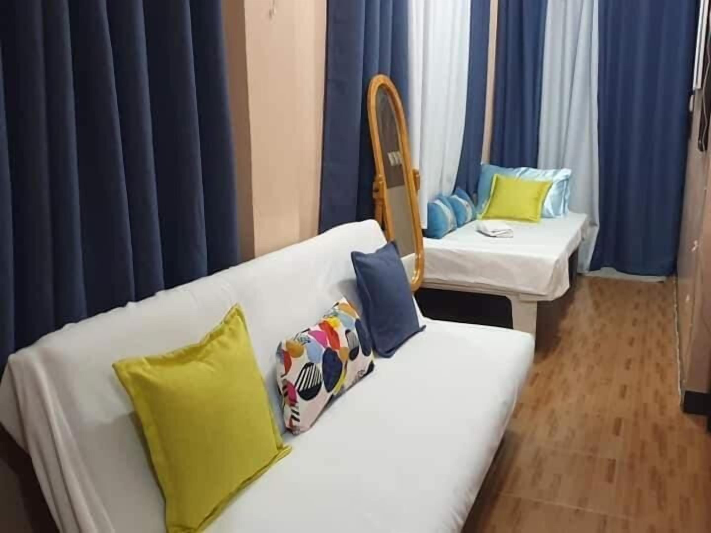 A hotel room with a single bed, a daybed, and a mirror on the wall.