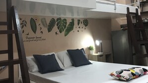 A bunk bed with a mural of leaves and birds on the wall, a small table with a plant, and a refrigerator in the background. - Palompon Traveler's Lodge (Palompon)