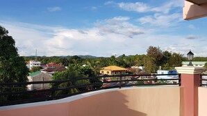 A balcony with a curved railing overlooking a residential area with houses and greenery. - Palompon Traveler's Lodge (Palompon)