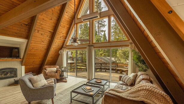 A spacious loft bedroom with a high ceiling, large windows, and a cozy seating area with a sofa and armchairs. - Cozy A Frame Cabin, Bass Lake, Ca-Acorn Falls  (Bass Lake)