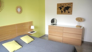 A bedroom with a bed, bedside table, lamp, dresser, and a world map on the wall.