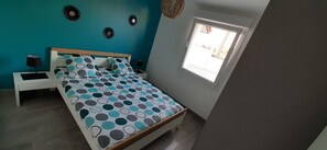 Um quarto com cama, mesas de cabeceira, janela e decoração nas paredes.