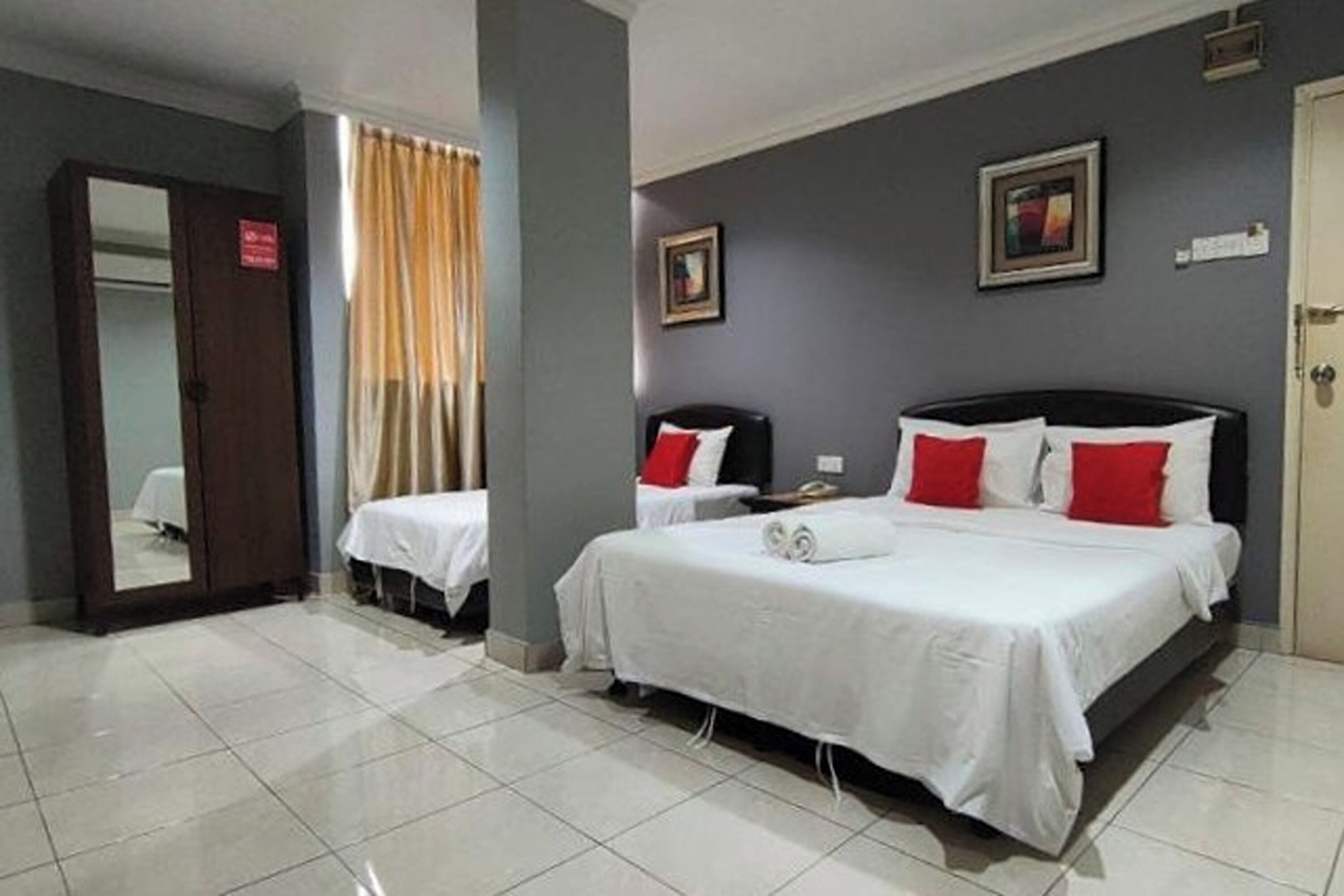 A hotel room with two beds, a mirror, a door, and a framed picture on the wall.
