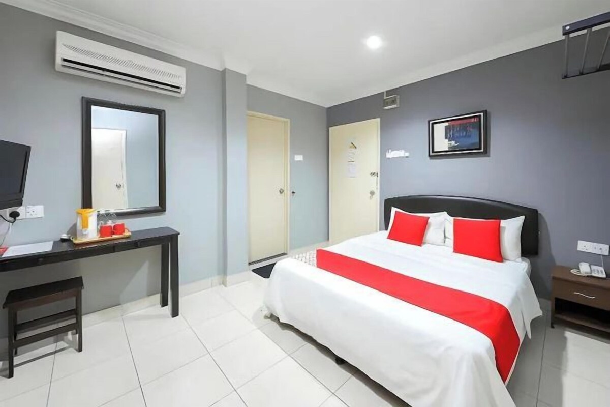 Habitación de hotel con cama, escritorio, silla, aire acondicionado, puerta y televisor montado en la pared.