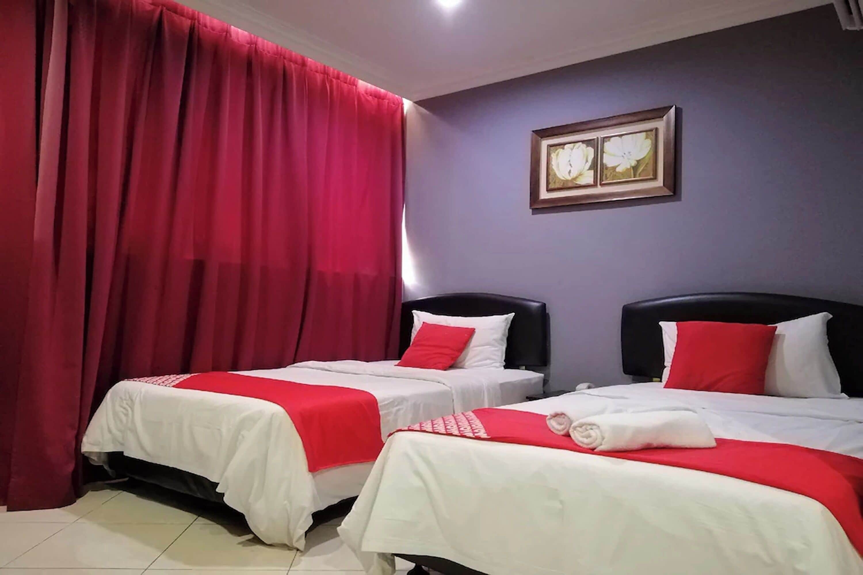 A hotel room with two beds, red curtains, a framed picture on the wall, and a tiled floor.