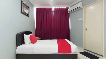 Un dormitorio con cama, puerta, equipo de aire acondicionado, un cuadro en la pared y ventana con cortinas.