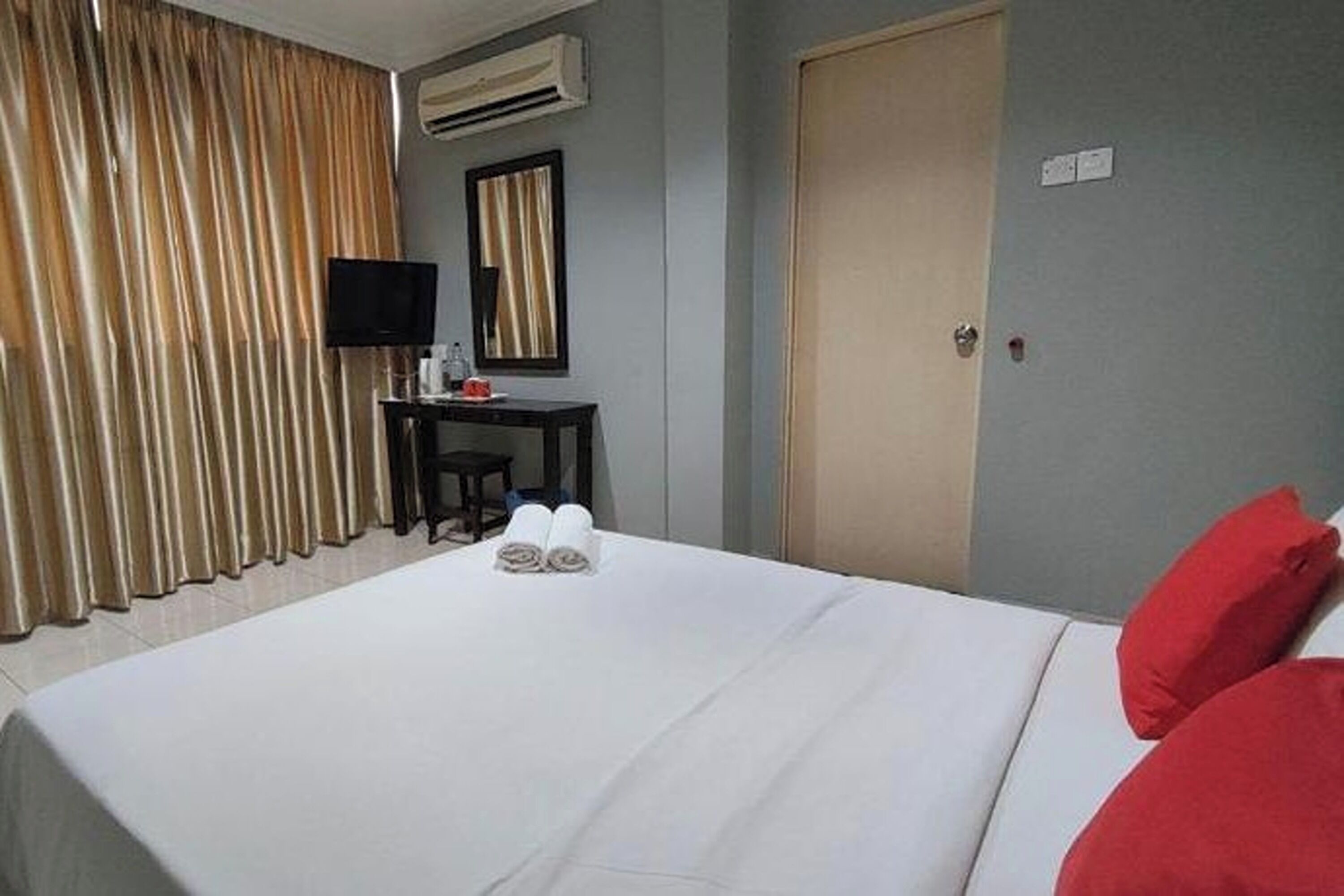 A hotel room with a bed, a desk, a television, and a door.
