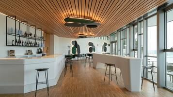 Un área de bar moderna con suelo de madera, taburetes y una exhibición de vinos.
