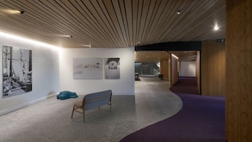 Une galerie d’art dotée d’un plancher incurvé, d’un plafond en bois et où sont exposées plusieurs œuvres d’art.