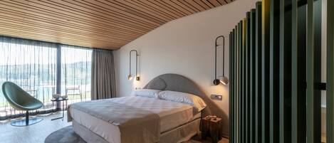 Un dormitorio moderno con una cama grande, un techo curvo y vistas al exterior.