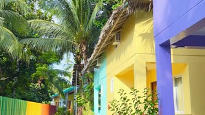 A narrow pathway flanked by colorful buildings and lush greenery, leading to a thatched-roof structure. - Indai Aquasports and Resort (Santa Fe)