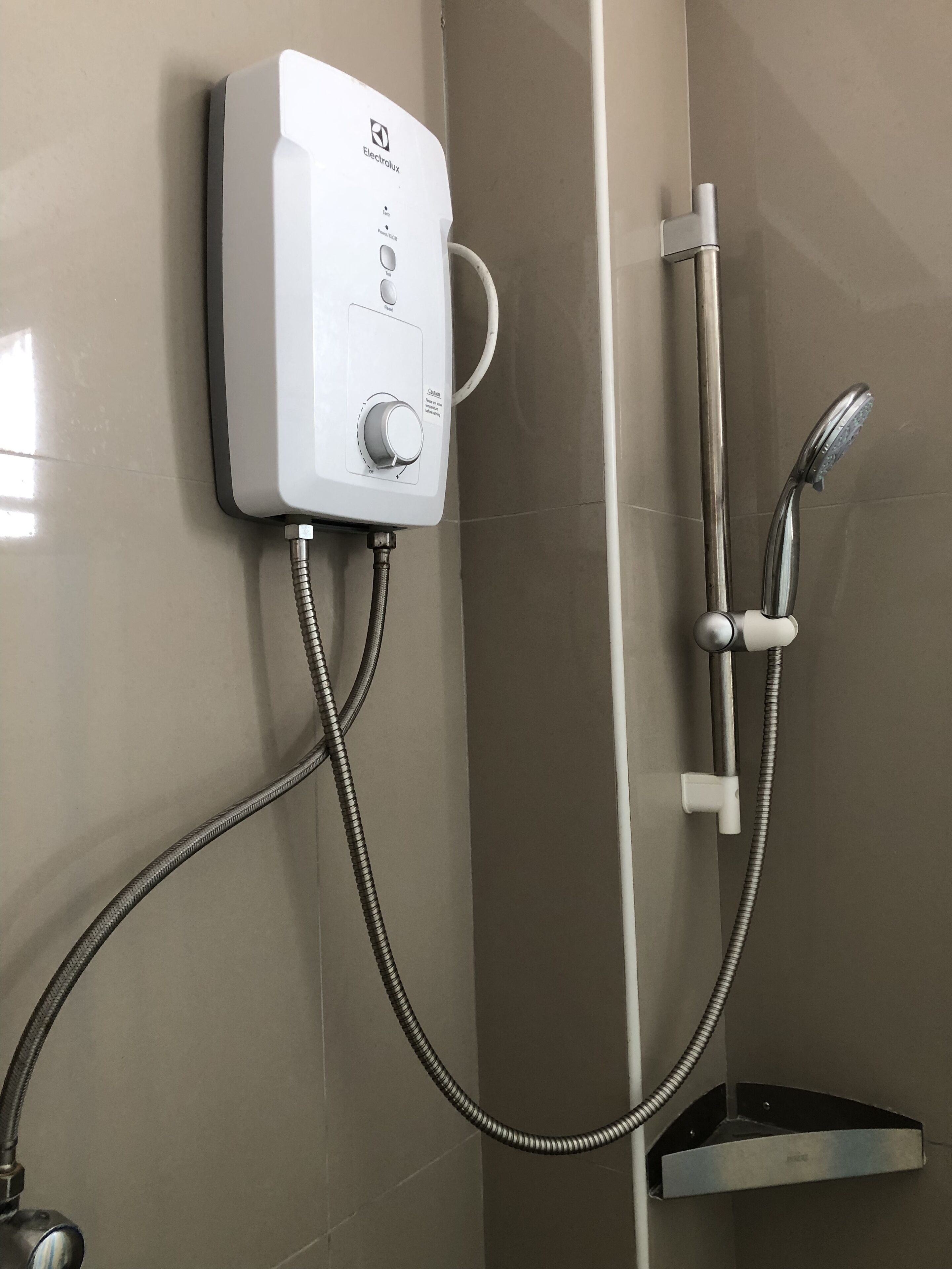 A shower with a wall-mounted control panel, a handheld showerhead, and a flexible hose.