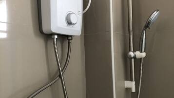 A shower with a wall-mounted control panel, a handheld showerhead, and a flexible hose.