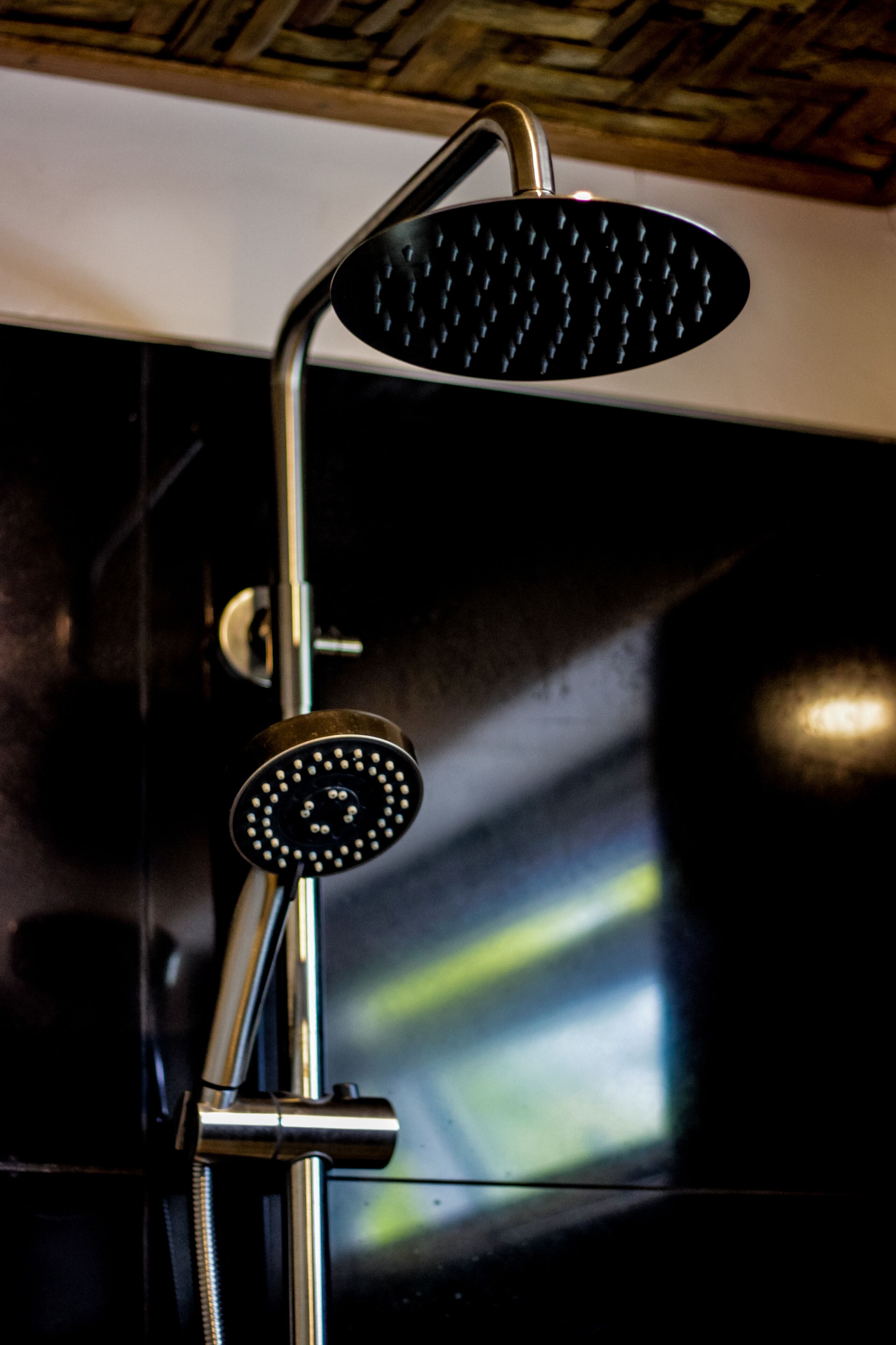 A shower with a handheld control and a wall-mounted panel.