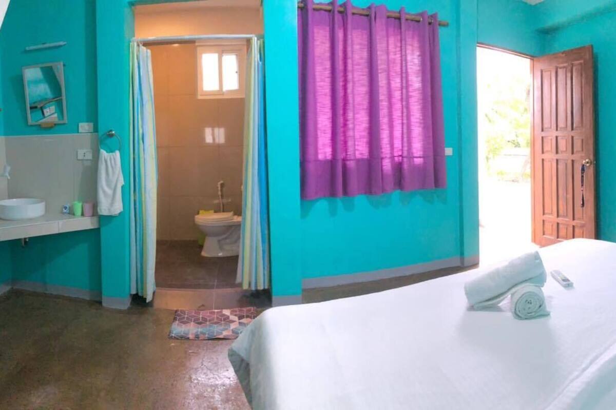 A bedroom with a bed, a bathroom with a shower, and a door leading outside.