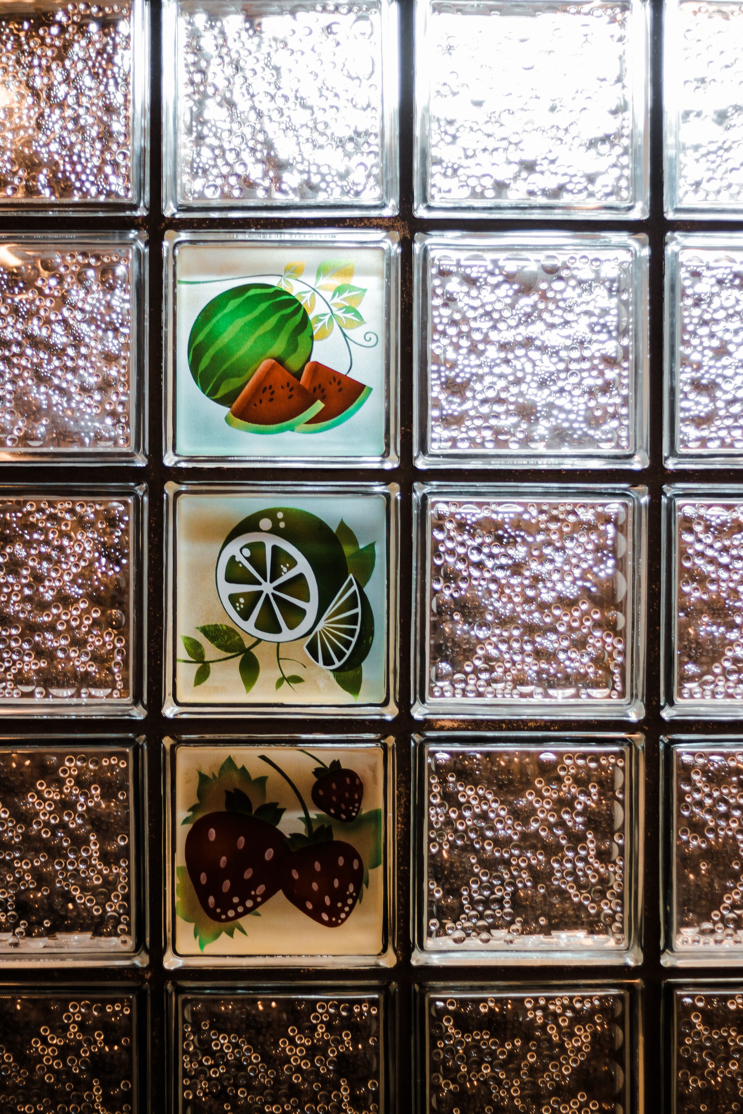 A wall with square tiles, some featuring fruit designs.