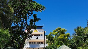 A beachside restaurant with outdoor seating, a thatched-roof structure, and a building with a sign indicating it is a restaurant and resort. - Indai Aquasports and Resort (Santa Fe)