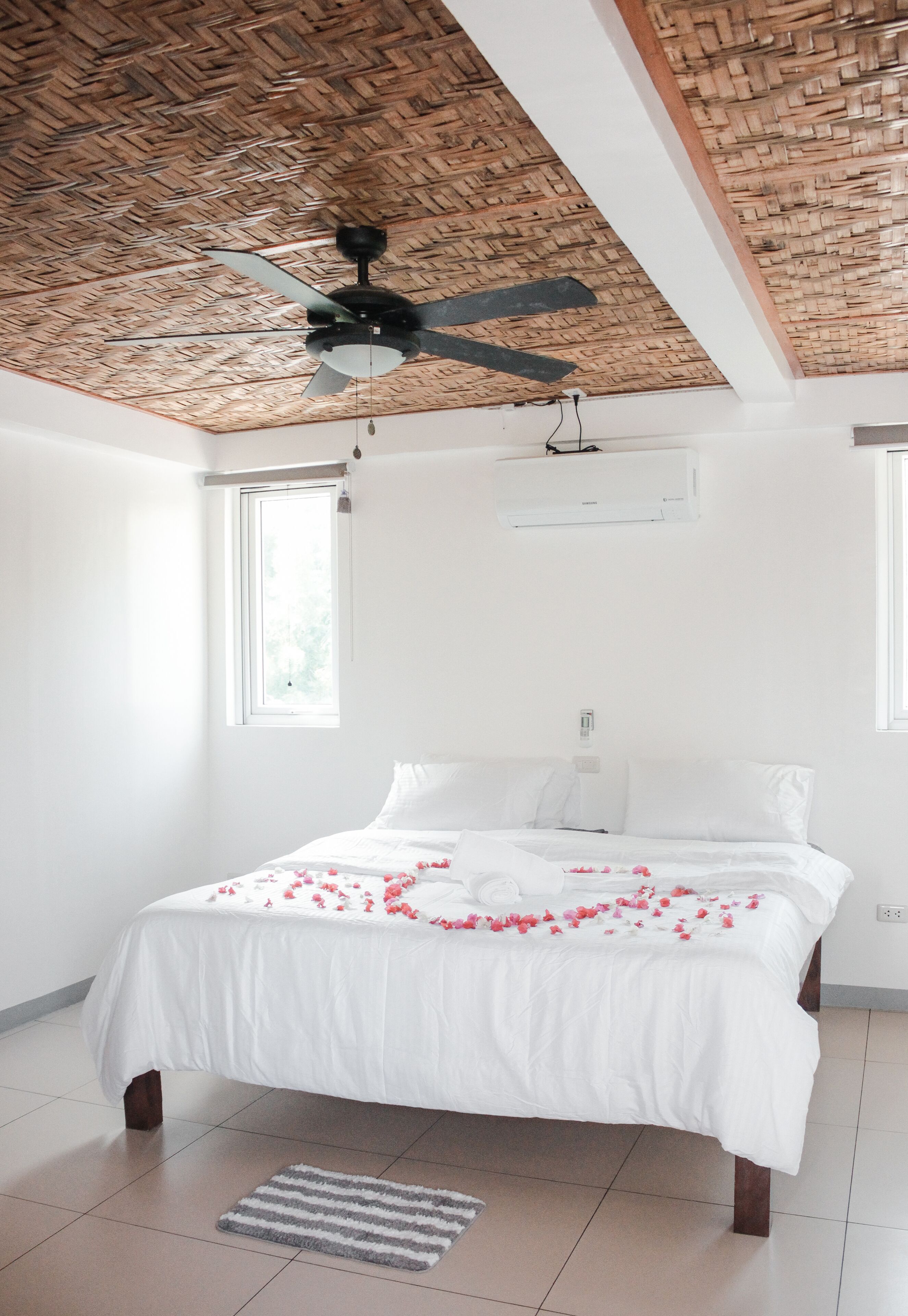 Un dormitorio con cama, ventilador de techo y ventana.