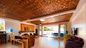 A spacious living area with a high ceiling, a large window, and a sliding glass door leading to an outdoor patio. - Indai Aquasports and Resort (Santa Fe)