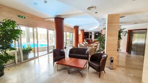Un hall con vista a la piscina, sillones de cuero, una mesa de madera y un diseño moderno.