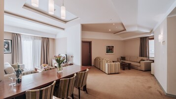 Una camera d'albergo con zona pranzo, divanetto e un quadro appeso al muro.