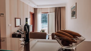Habitación de hotel con comedor, una botella de vino, un teléfono y vistas al exterior.