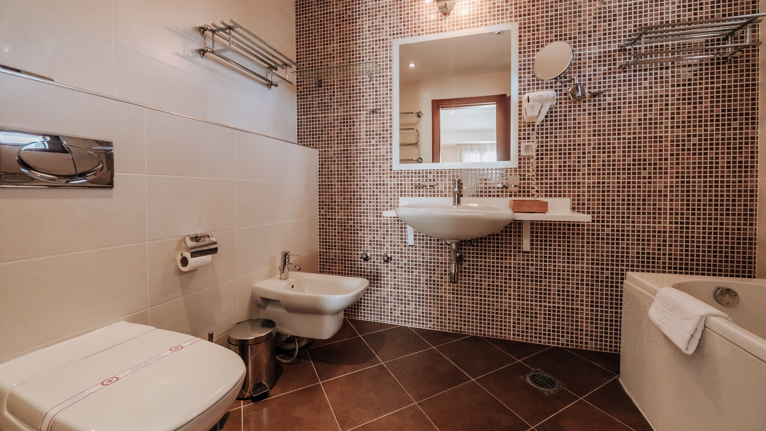 Ein Badezimmer mit Waschbecken, Spiegel, Handtuchhalter und Toilette.