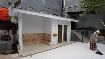 A building with a tiled entrance area, a bench, and a staircase leading to an upper level.