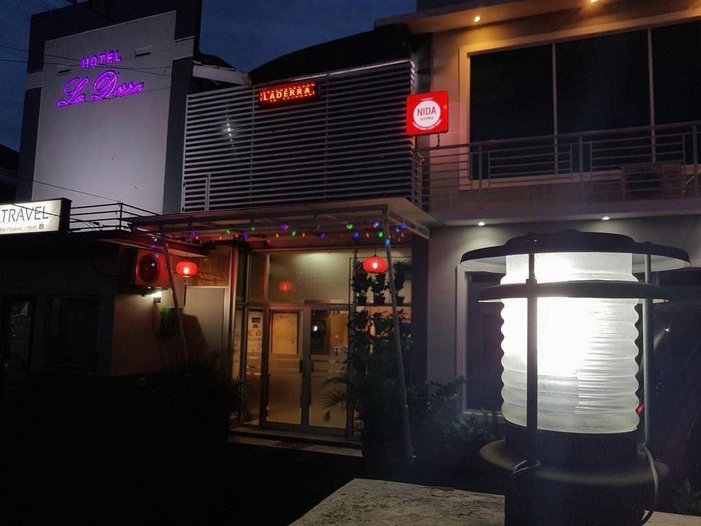 A hotel with a neon sign, a visible entrance, and a street lamp.