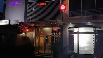 A hotel with a neon sign, a visible entrance, and a street lamp.