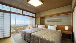 Habitación de hotel con dos camas, vista al mar, suelo de tatami y pared de estilo tradicional japonés.