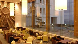 Un vestíbulo de hotel con zonas de estar, ventanas amplias y vistas al exterior.