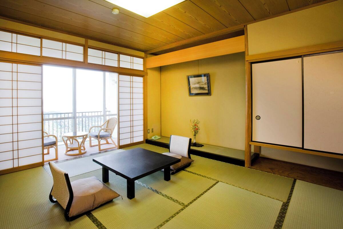 Um quarto japonês tradicional com tatames, uma mesa baixa e uma porta deslizante.